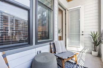A small porch with a chair and a table and windows